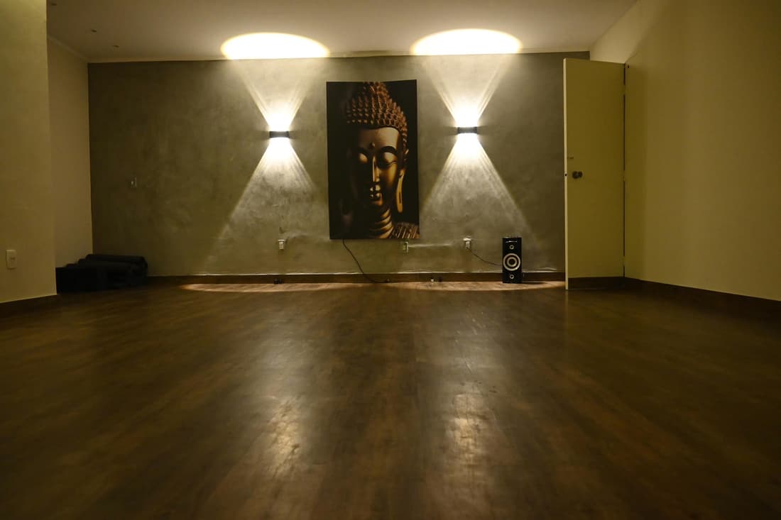 Sala de yoga do Yoga du Ville — painel Buda iluminado e piso amadeirado